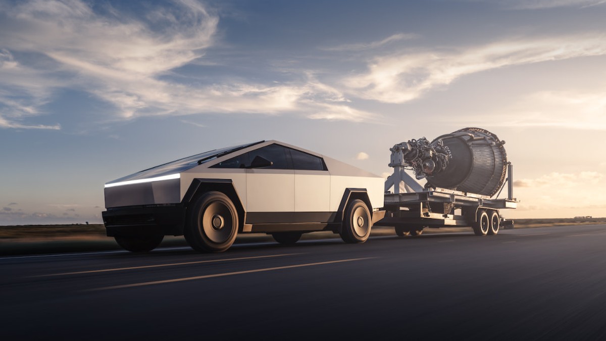 Tesla'nın resmi Cybertruck görseli: gün batımında asfalt yolda römork çeken gümüş renkli Cybertruck